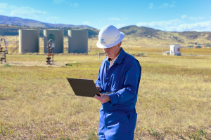 Oil field worker monitoring emissions using a laptop